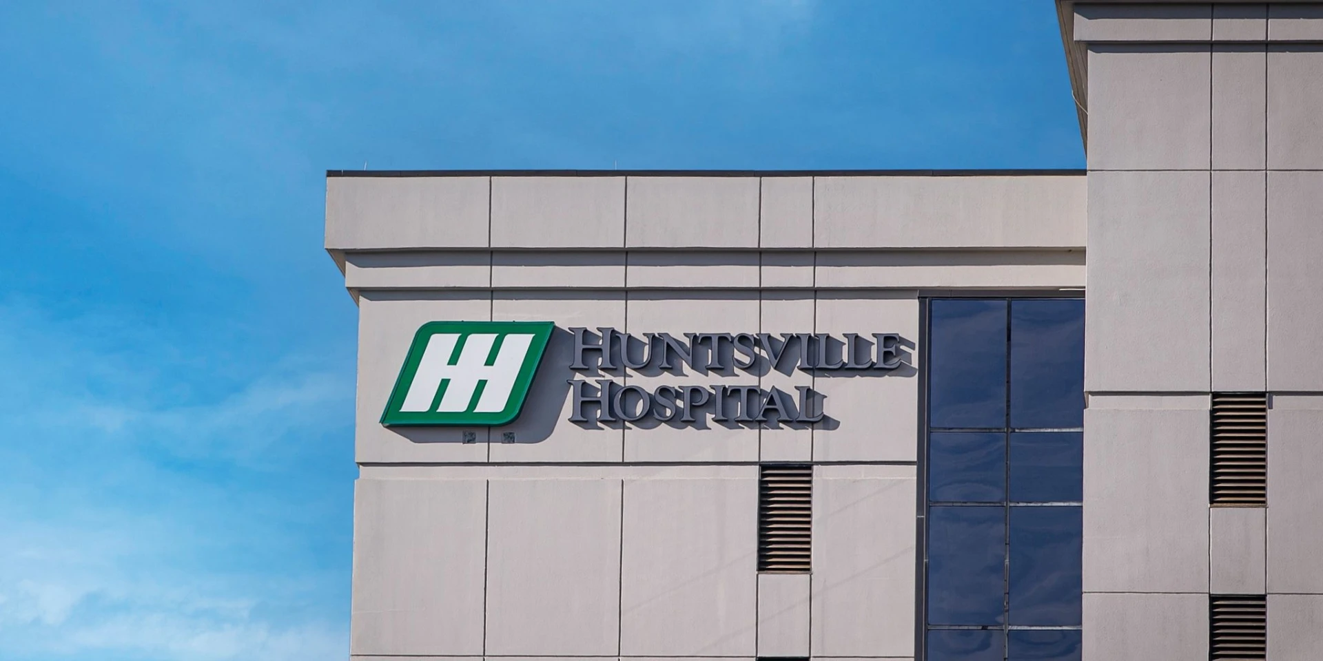 Huntsville Hospital sign and logo on the hospital building against a blue sky